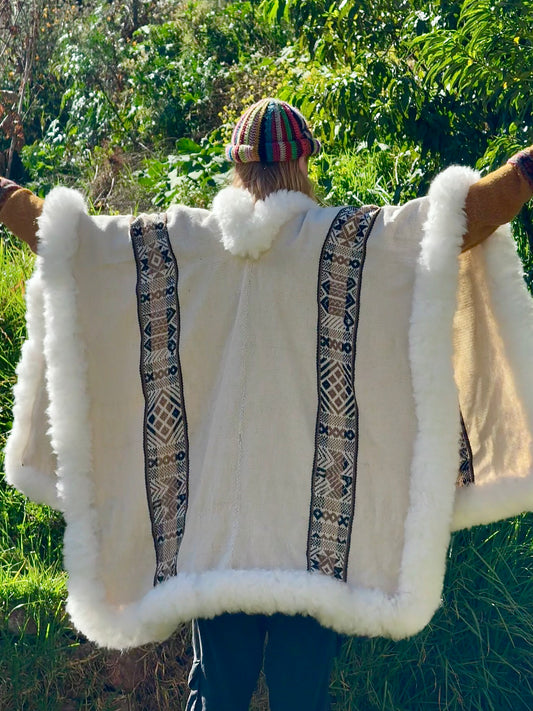 Person wearing a white fur-lined garment with patterned trim in a natural setting
