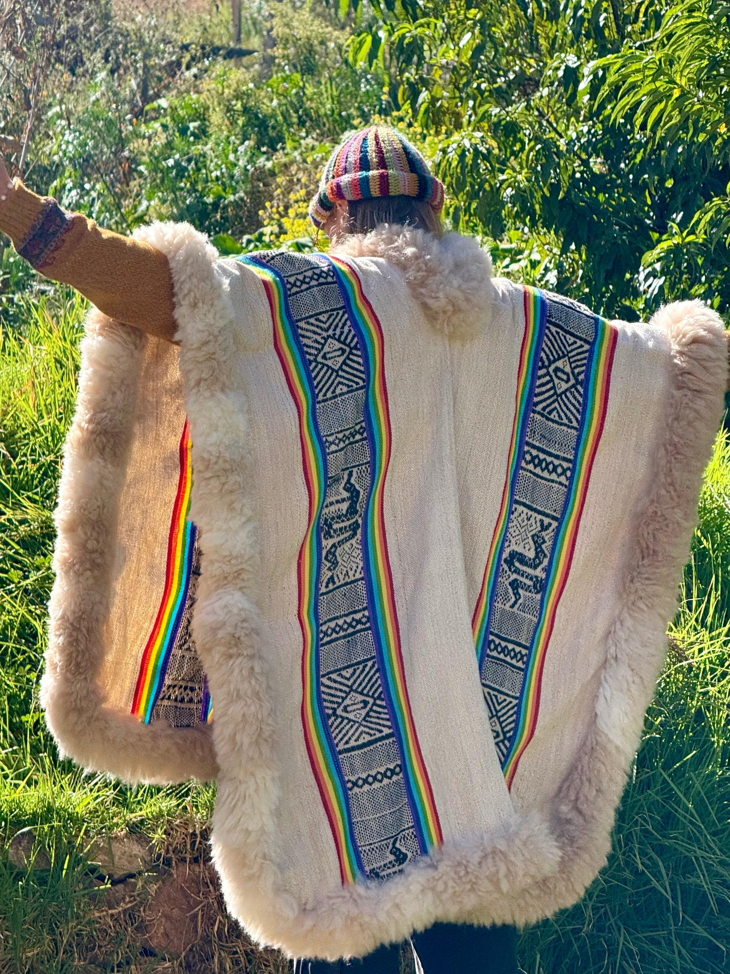 Person wearing a traditional garment with colorful patterns in a natural setting